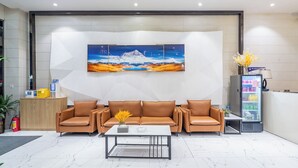 Eine Lobby mit einer Rezeption, einer Sofagarnitur, einem Couchtisch und einem Getränkeangebot.