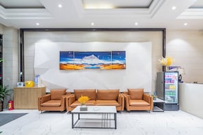 Eine Lobby mit einer Rezeption, einer Sofagarnitur, einem Couchtisch und einem Getränkeangebot.