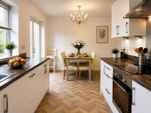 Une cuisine moderne avec un parquet en chevrons, des plans de travail en bois et des appareils électroménagers en acier inoxydable.
