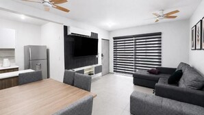Ein stilvoller Wohnraum mit Essbereich, einer Couch und einem Fernseher.