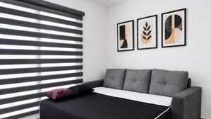 Ein Schlafzimmer mit einem Bett, einem Deckenventilator, einem Fenster mit Jalousien und drei gerahmten Kunstwerken an der Wand.