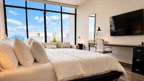 Ein modernes Schlafzimmer mit einem großen Bett, einem Schreibtisch und einem Fernseher.