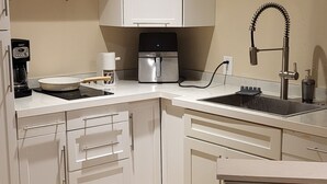 Eine Küche mit weißen Schränken, einer Kaffeemaschine, einem Spülbecken und einem gefliesten Boden.