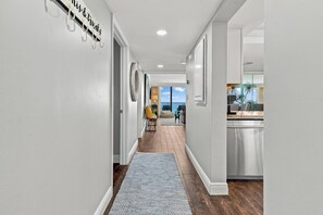A hallway leading to a balcony with a view, a kitchen area, and a sign on the wall. - Edgewater T2 703 - 3 Bedrooms! (Panama City Beach)