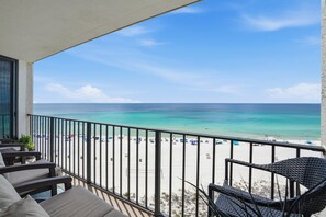 A balcony with a view of a beach, outdoor seating, and a railing. - Edgewater T2 703 - 3 Bedrooms! (Panama City Beach)