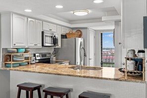 A modern kitchen with white cabinetry, stainless steel appliances, and a granite countertop. - Edgewater T2 703 - 3 Bedrooms! (Panama City Beach)
