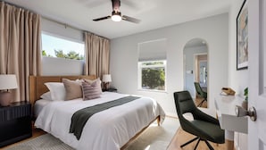A modern hotel room with a large bed, a ceiling fan, a view of the outdoors, and a seating area. - Theater, Spa, Gym, & Vinyls: 2 Homes, 1 Epic Stay! (Austin)