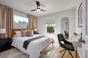 A modern hotel room with a large bed, a ceiling fan, a view of the outdoors, and a seating area. - Theater, Spa, Gym, & Vinyls: 2 Homes, 1 Epic Stay! (Austin)
