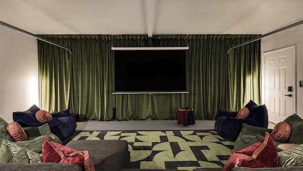 A room with a large flat-screen TV, green curtains, and two bean bag chairs. - Theater, Spa, Gym, & Vinyls: 2 Homes, 1 Epic Stay! (Austin)