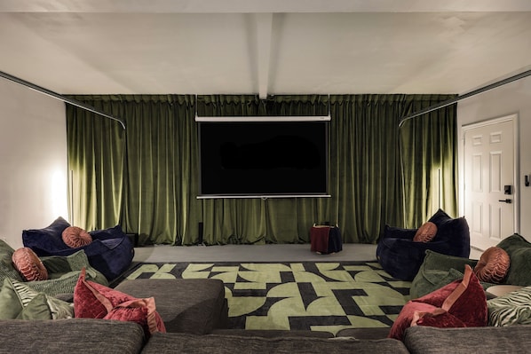 A room with a large flat-screen TV, green curtains, and two bean bag chairs. - Theater, Spa, Gym, & Vinyls: 2 Homes, 1 Epic Stay! (Austin)