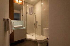 Ein modernes Badezimmer mit einer Glasdusche, einem weißen Waschbecken und einer Toilette.
