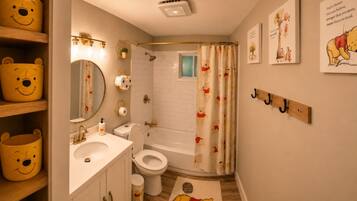 A bathroom with a toilet, sink, and shower curtain featuring cartoon characters.