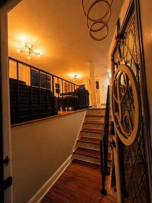 Eine Treppe mit Handlauf, eine Wand mit dekorativem Spiegel und einer Deckenleuchte.