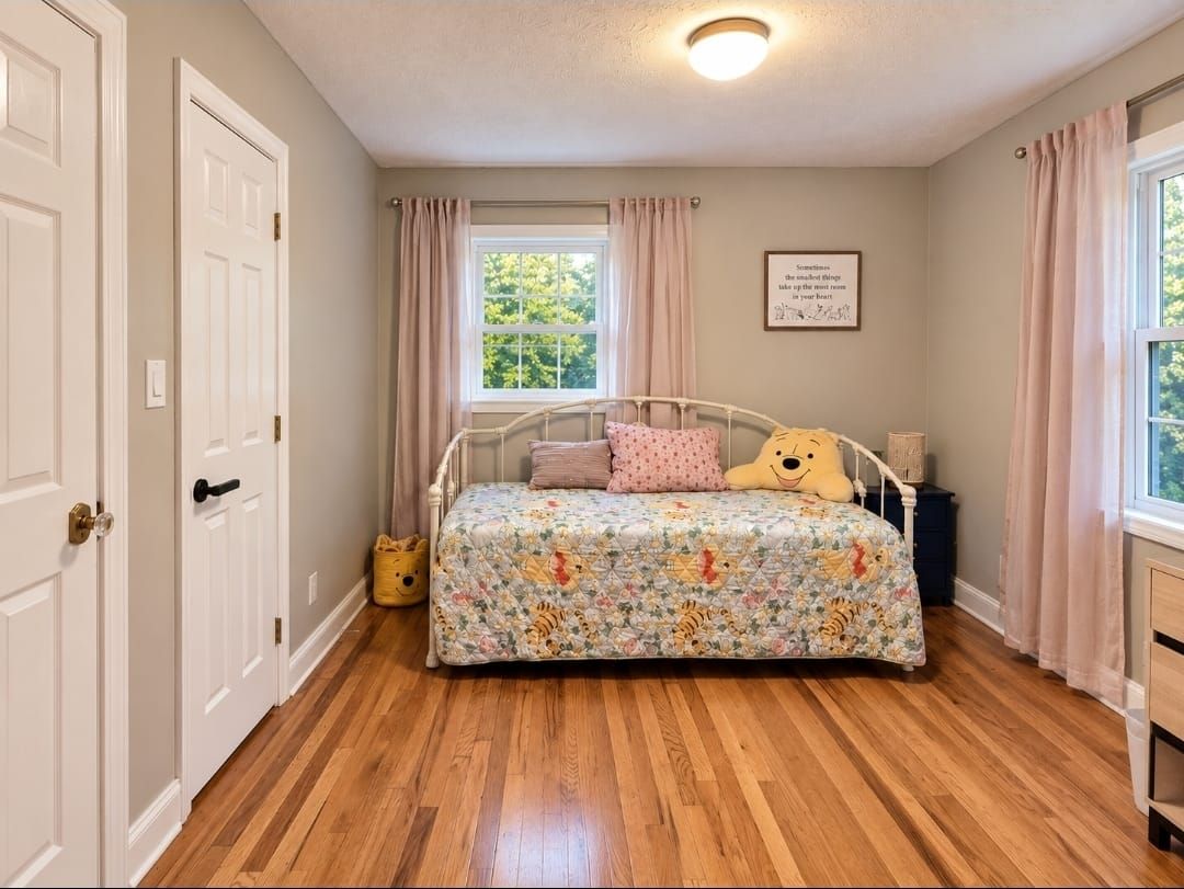 Une chambre à coucher avec un lit, une fenêtre, une porte et un luminaire fixé au mur.