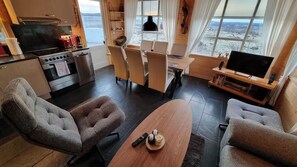 Una sala de estar moderna con un ventanal grande, un comedor y una cocina con estufa y horno.