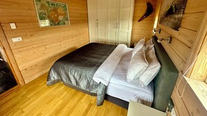 Un dormitorio de cabaña de madera con cama, armario blanco y un mapa en la pared.