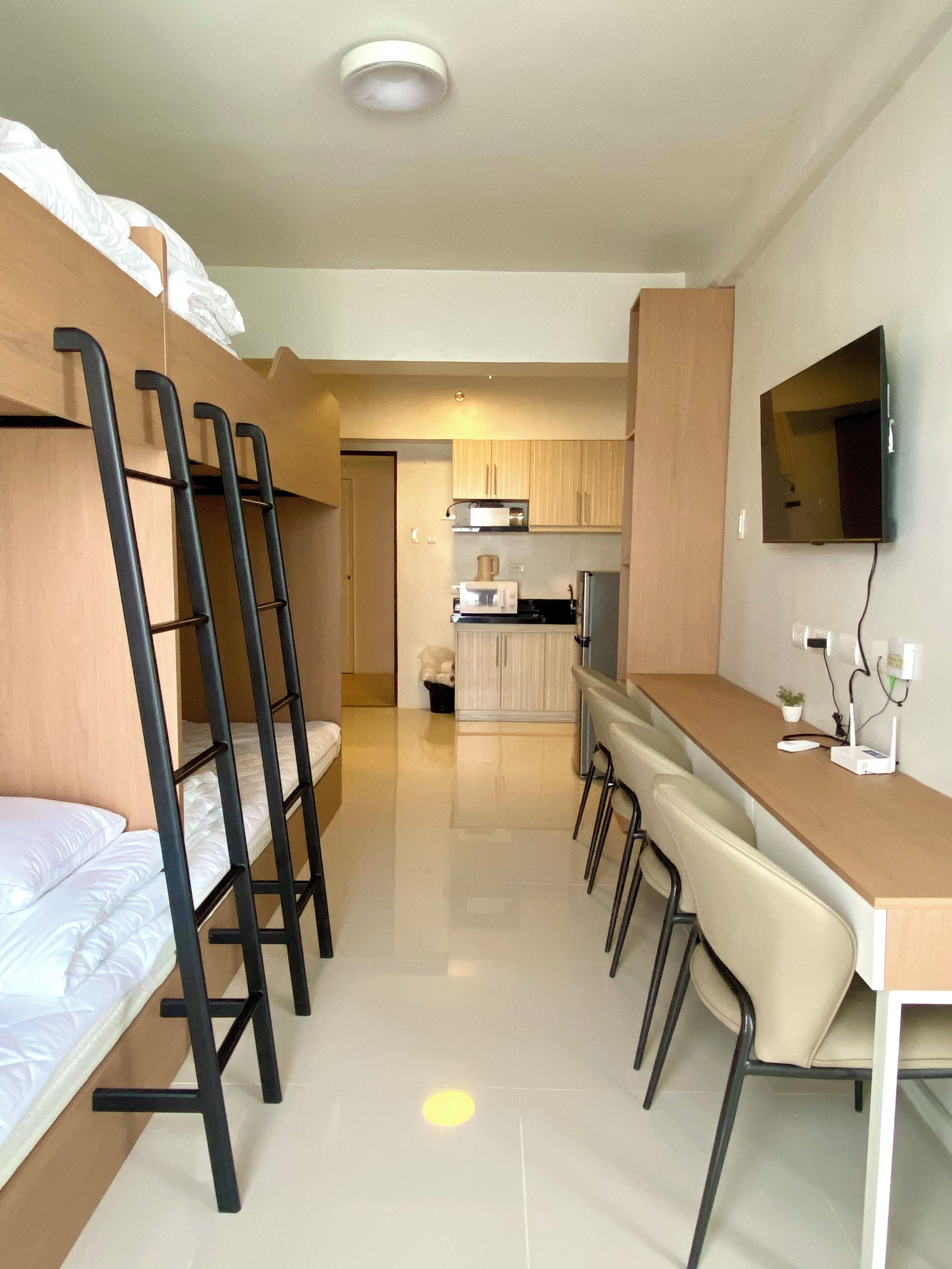 Een kleine kamer met stapelbedden, een kitchenette, een flatscreen-tv en een eethoek.