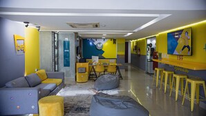 Un interior moderno con un sofá, un reposapiés amarillo y una zona de bar con taburetes.