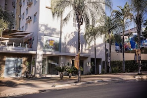 A modern building with a large glass facade, palm trees, and a sign that reads 'be living.' - Be Living (Vespasiano)
