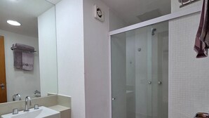 Un baño moderno con ducha envuelta en vidrio, un lavabo blanco y un inodoro.