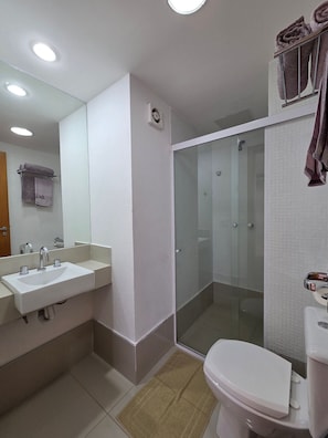 Un baño moderno con ducha envuelta en vidrio, un lavabo blanco y un inodoro.