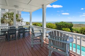 Ett takförsett utomhusområde med en pool, sittplatser och utsikt över stranden och havet.