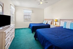 Ein Hotelzimmer mit zwei Betten, einem Fernseher auf einer Kommode und einem Deckenventilator.