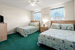 A room with two beds, a ceiling fan, and a TV on a stand. - Paradise awaits at this elegant marsh condo across street from ocean w/pool, courtyard, sundeck (North Myrtle Beach)