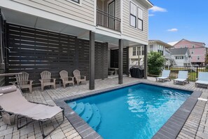 A swimming pool with lounge chairs and a covered patio area. - Tides & Vibes: Spacious 5BR Retreat w/ Private Pool, across the street from the beach (North Myrtle Beach)