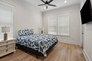 A bedroom with a bed, nightstands, a ceiling fan, and a TV mounted on the wall. - Tides & Vibes: Spacious 5BR Retreat w/ Private Pool, across the street from the beach (North Myrtle Beach)