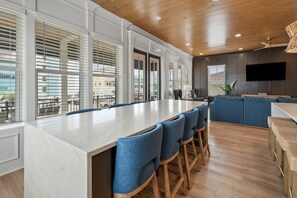 Une cuisine moderne dotée d’un grand îlot central, de tabourets de bar et d’un téléviseur à écran plat fixé au mur.