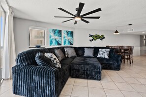 A modern living room with a sectional sofa, a ceiling fan, and artwork on the walls. - Oceanfront 4BR condo with stunning views, pools, lazy river, and prime location near Main Street! (North Myrtle Beach)
