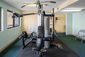 A gym with exercise machines, a bench, and a notice sign. - Oceanfront 4BR condo with stunning views, pools, lazy river, and prime location near Main Street! (North Myrtle Beach)