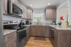 A modern kitchen with a built-in oven, microwave, and coffee maker. - 6BR ocean-view home in Crescent Beach with beach access and parking (North Myrtle Beach)