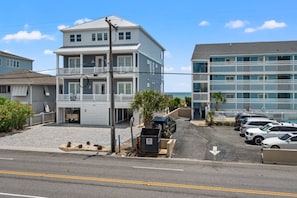 A coastal hotel with a two-story structure, a parking lot, and a view of the ocean. - 6BR ocean-view home in Crescent Beach with beach access and parking (North Myrtle Beach)