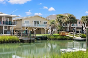A waterfront property with multiple buildings, a dock, and a calm water body. - Waterfront channel home close to beach - fishing and crabbing (North Myrtle Beach)
