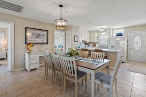 A spacious kitchen with a dining area, featuring a chandelier, white cabinetry, and a tiled floor. - Waterfront channel home close to beach - fishing and crabbing (North Myrtle Beach)