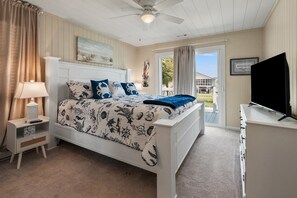 A bedroom with a bed, nightstand, lamp, and a television. - Waterfront channel home close to beach - fishing and crabbing (North Myrtle Beach)