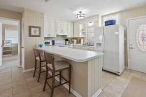 A kitchen with a central island, white cabinetry, and a refrigerator. - Waterfront channel home close to beach - fishing and crabbing (North Myrtle Beach)