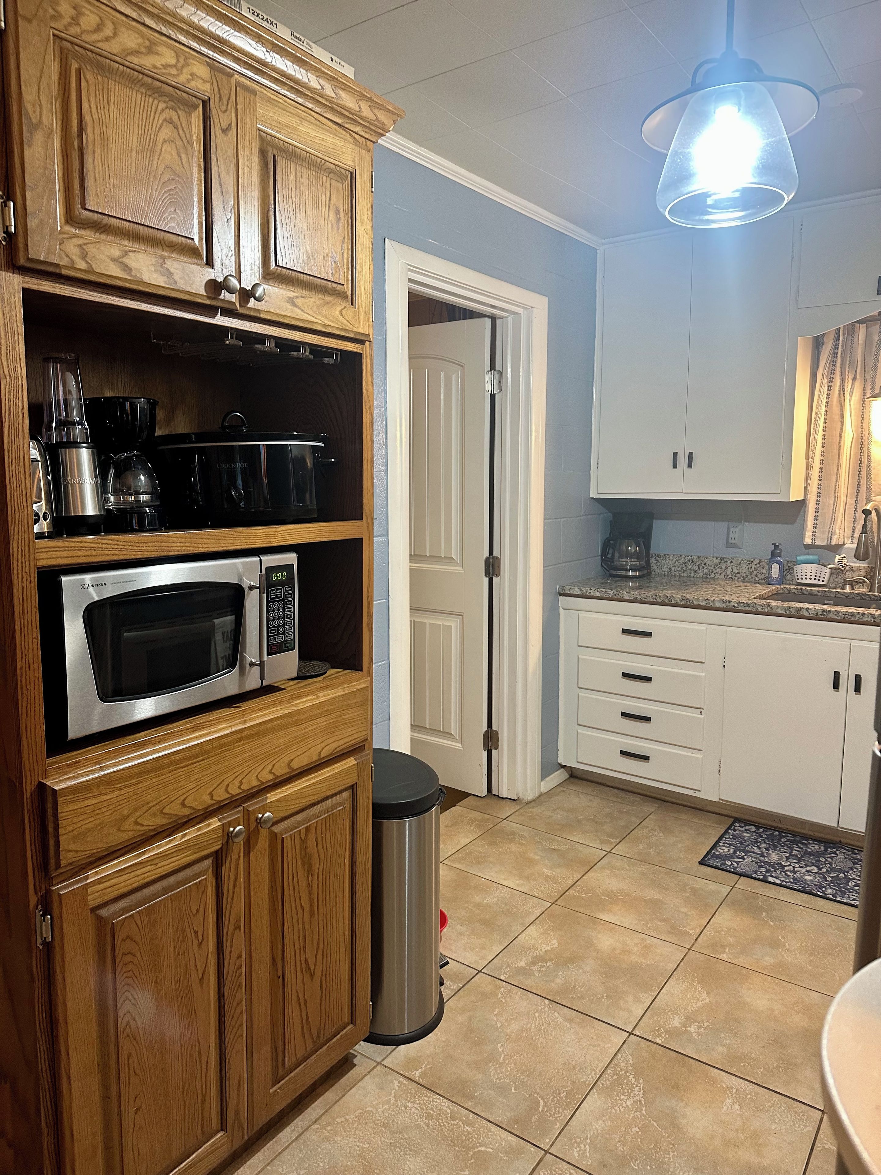 A kitchen with wooden cabinets, a stainless steel microwave, and a coffee maker.