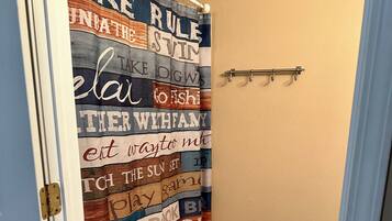 A bathroom with a shower curtain featuring various phrases and a small rug on the floor.
