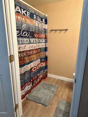 Een badkamer met een douchegordijn met verschillende zinnen en een klein vloerkleed.