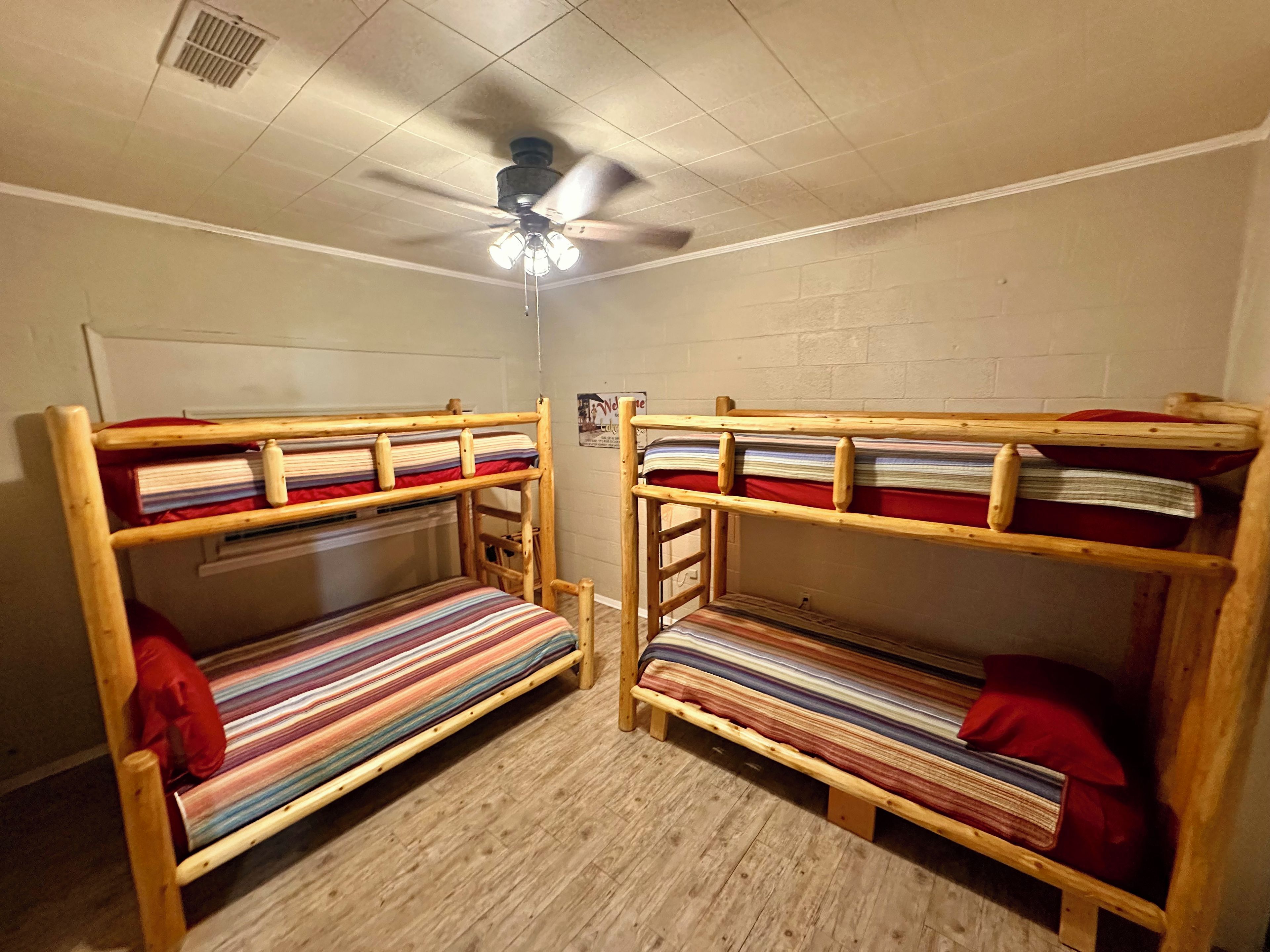 Ein Zimmer mit zwei Etagenbetten, einem Deckenventilator und einer Lampe.