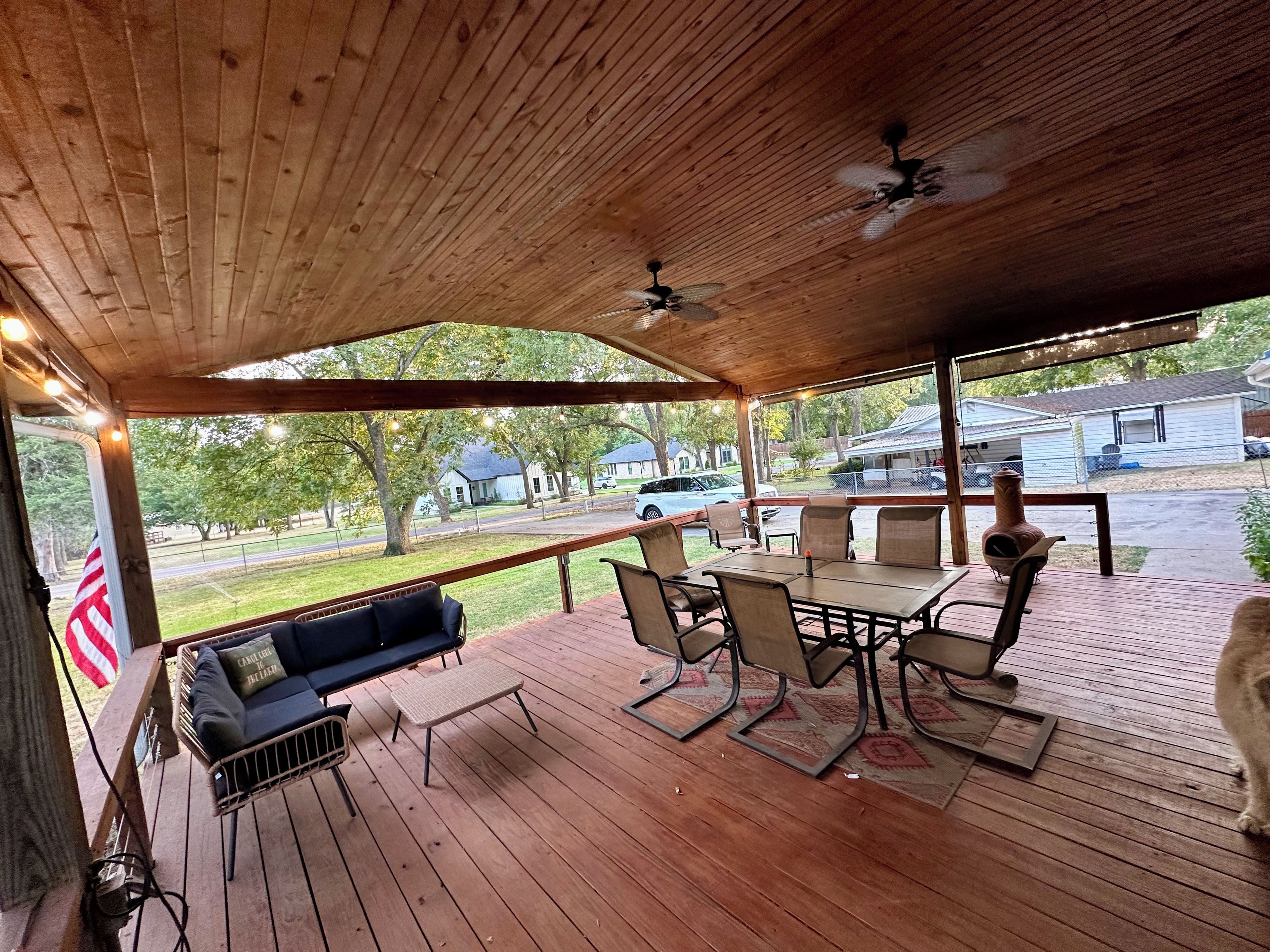 A covered outdoor seating area with a table and chairs, a sofa, and a ceiling fan.