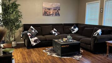 A living room with a dark brown sofa, a coffee table, a ceiling fan, and a painting on the wall.
