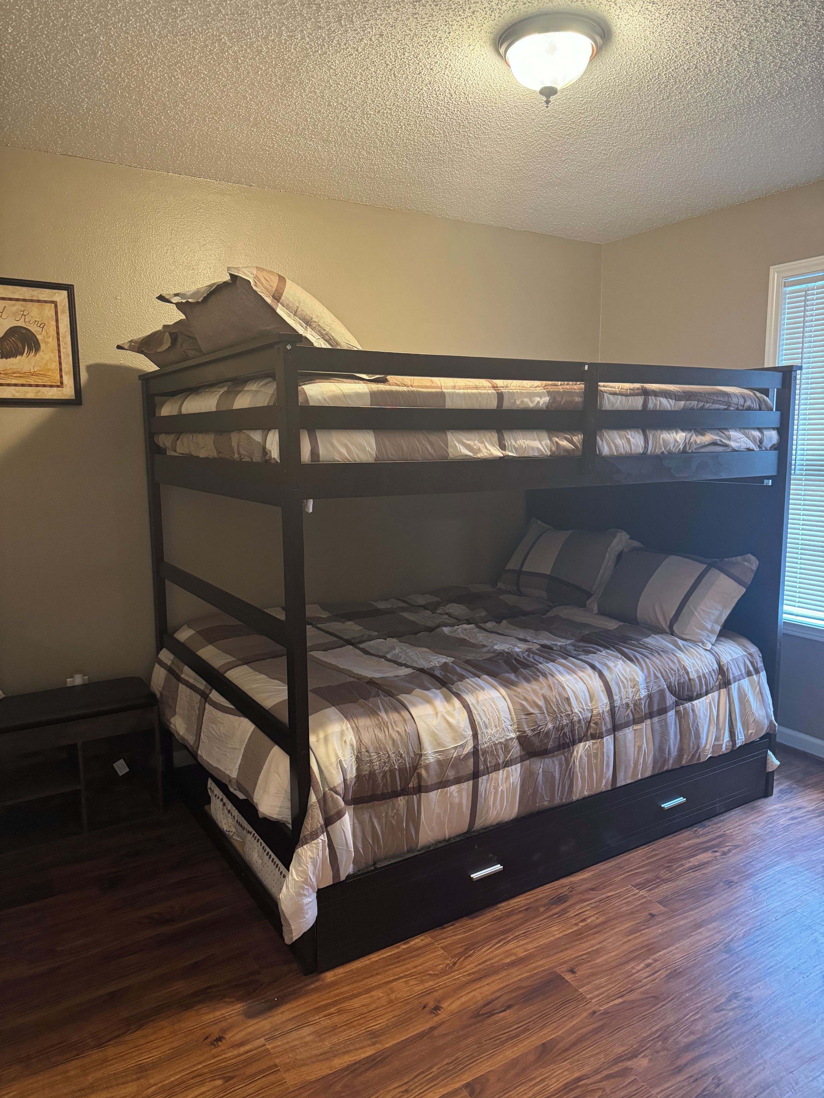 A bunk bed with a headboard, a bedside table, and a wall-mounted picture frame.