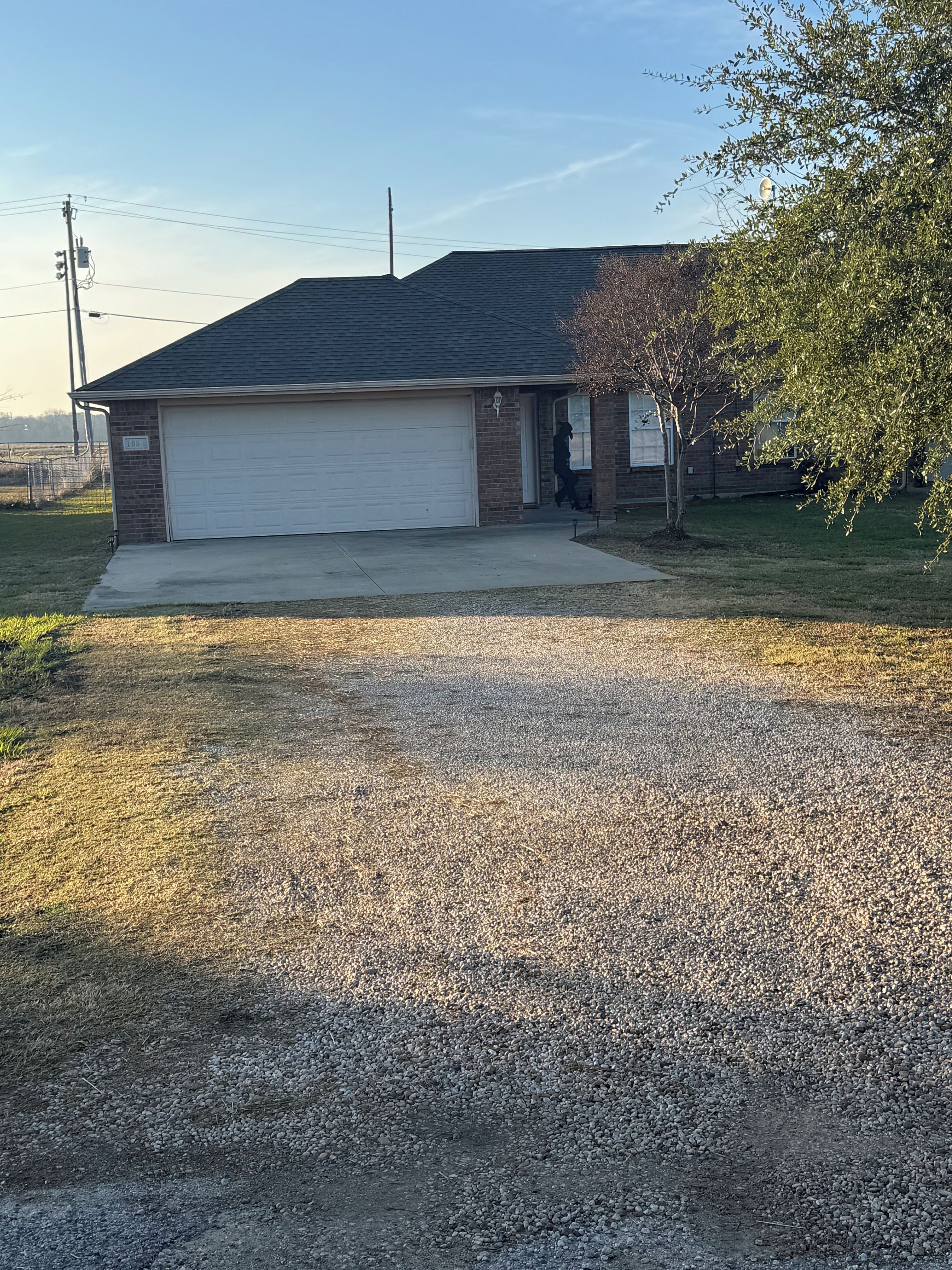 A residential house with a garage, a driveway, and a tree.