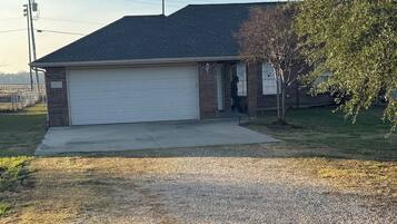 A residential house with a garage, a driveway, and a tree.