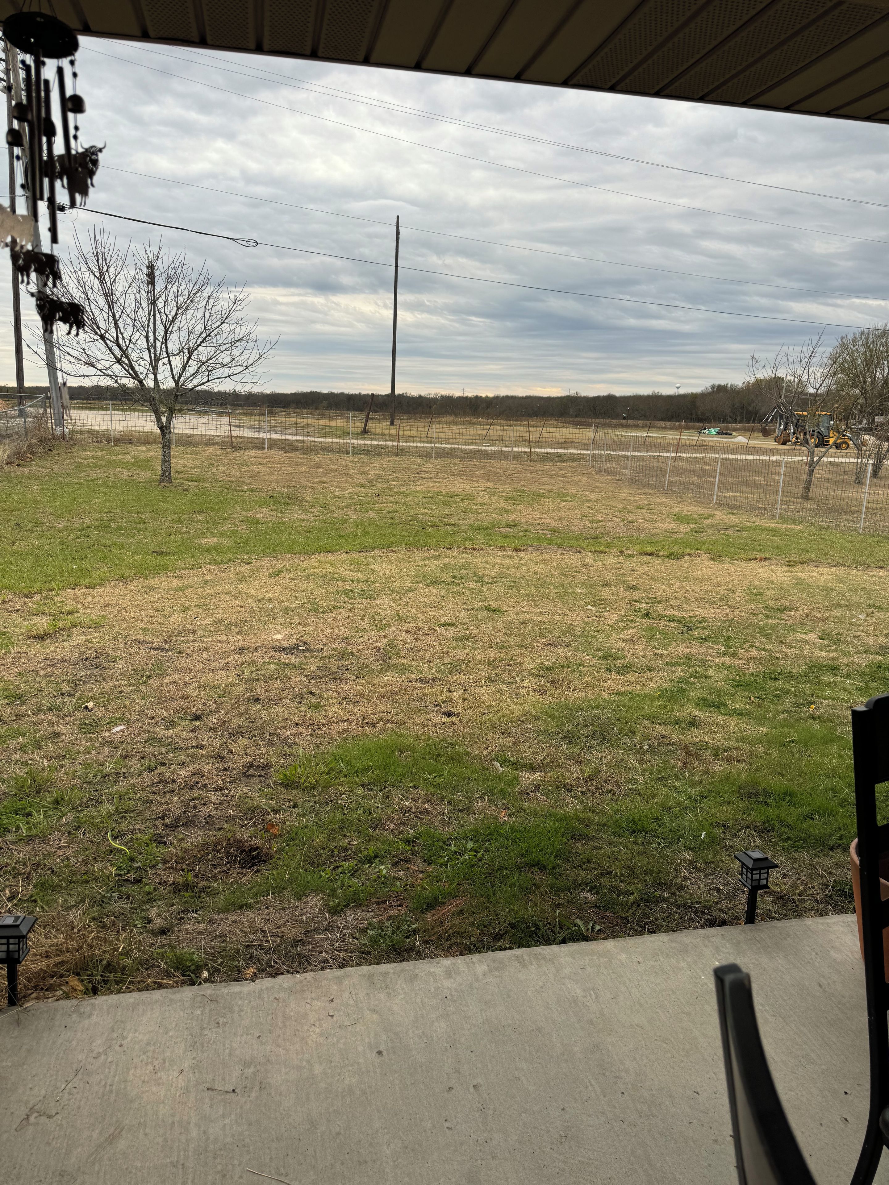 An outdoor area with a fenced field, a tree, and a tractor.