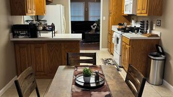 A kitchen with wooden cabinets, a dining table with chairs, and a view into the living area.
